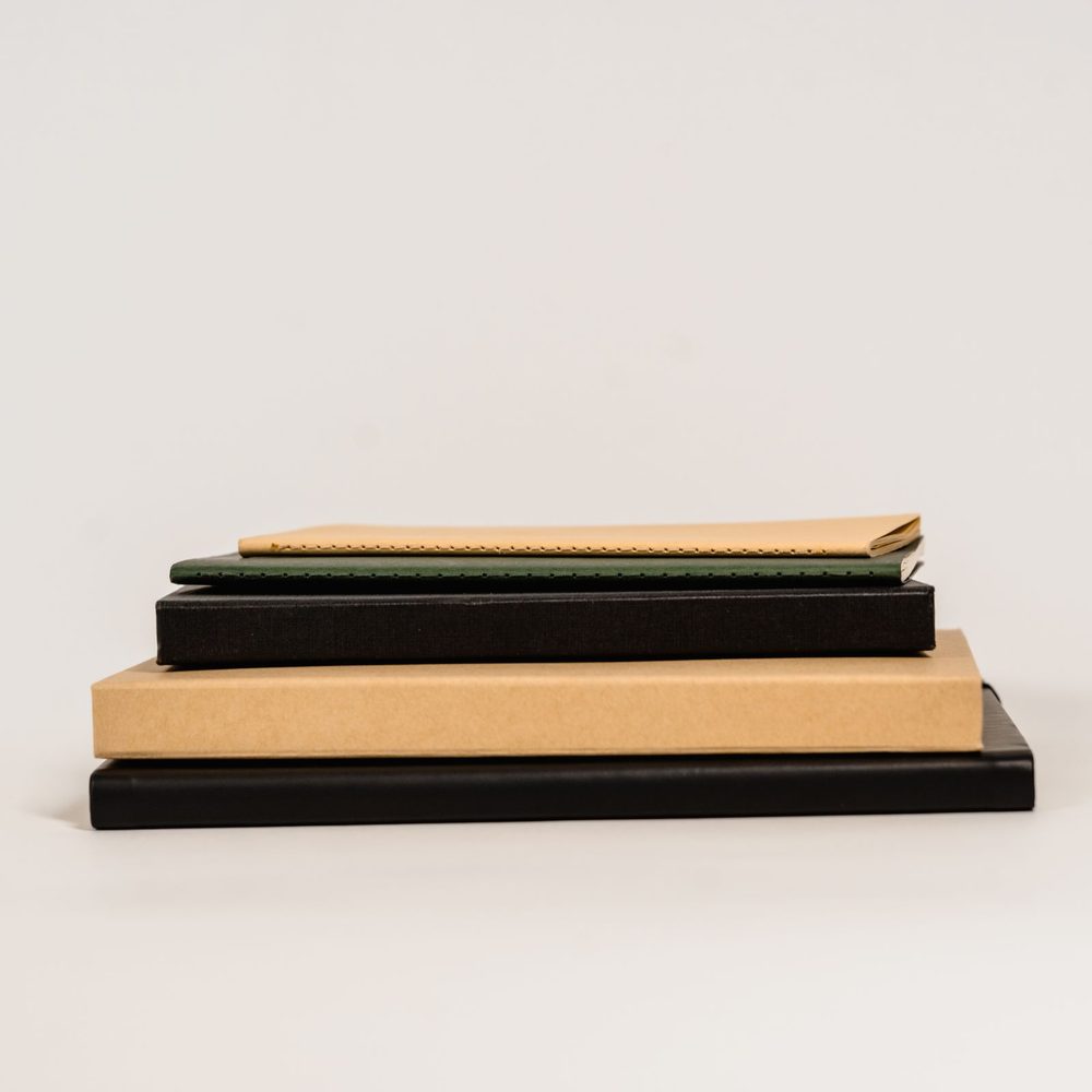A neat stack of closed notebooks on a pale surface